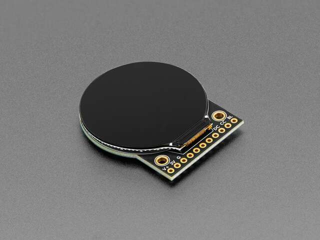 A 1.28 inch round glass display affixed to a black circuit board that is also round, but squared off about a quarter the circumference to expose 10 gold round pads used for electrical connections.